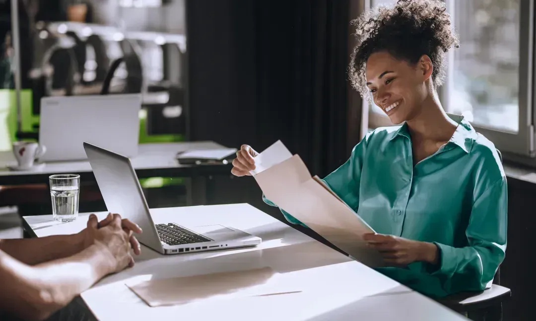 Mulher sorridente lendo um documento numa mesa de reunião