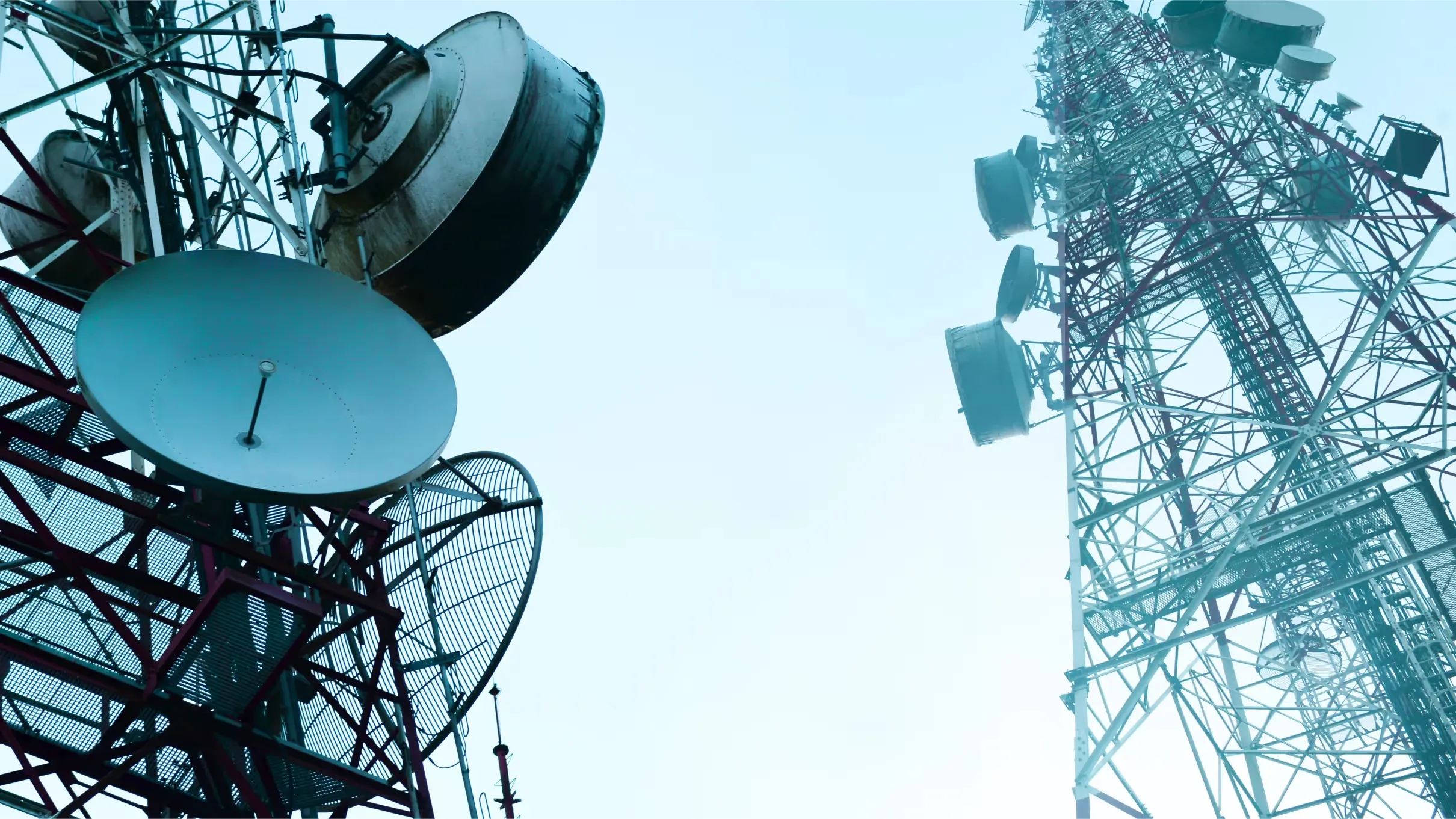 Two telecommunications towers with satellite dishes against the sky