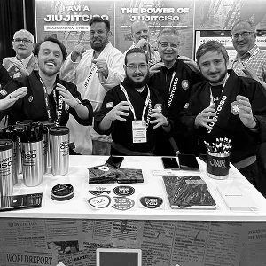 Group in JiujitCISO gis in fighting poses at a booth table with Segura™ giveaways