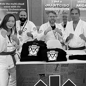 Five people in gis striking fighting poses behind a table of JiujitCISO T-shirts