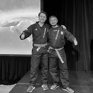 Two men in JiujitCISO gis posing on stage in front of a screen