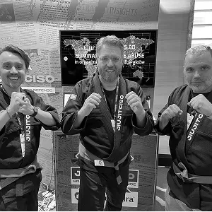 Three men in JiujitCISO gis raising their fists at the Segura™ booth