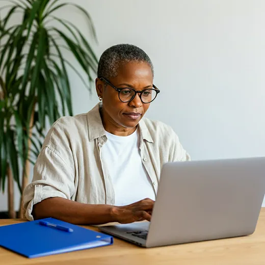 Mulher de óculos estudando concentrada diante de um laptop