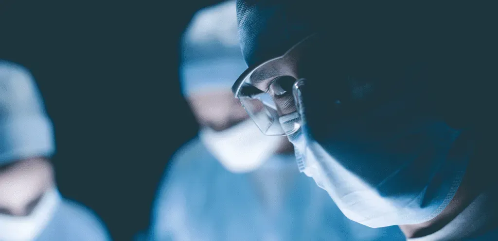 Masked medical team during a procedure in a dimly lit room