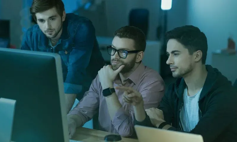 Three men analysing something on a computer screen