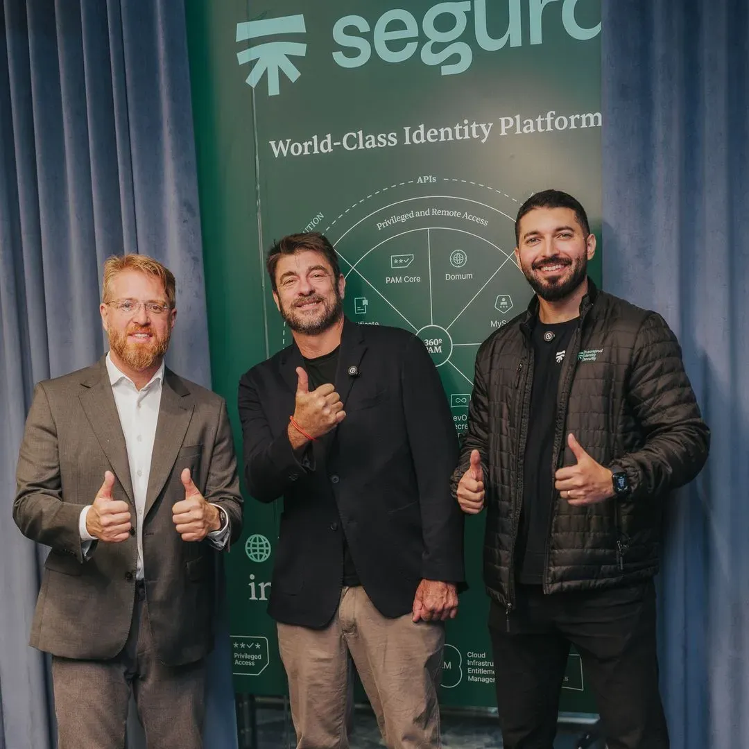 Three executives giving a thumbs-up in front of the Segura™ “World-Class Identity Platform” panel