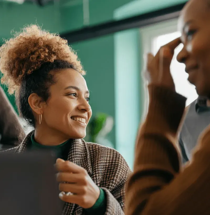 Profissional sorridente conversa com colegas em uma reunião de trabalho